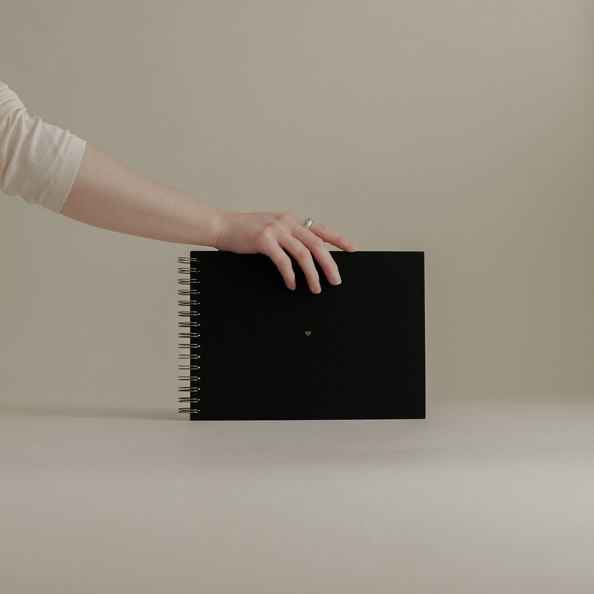 Czarny album na zdjęcia od marki KAIKO. Album fotograficzny na spirali i ze złoconym serduszkiem na środku, w kolorze miedzianym.