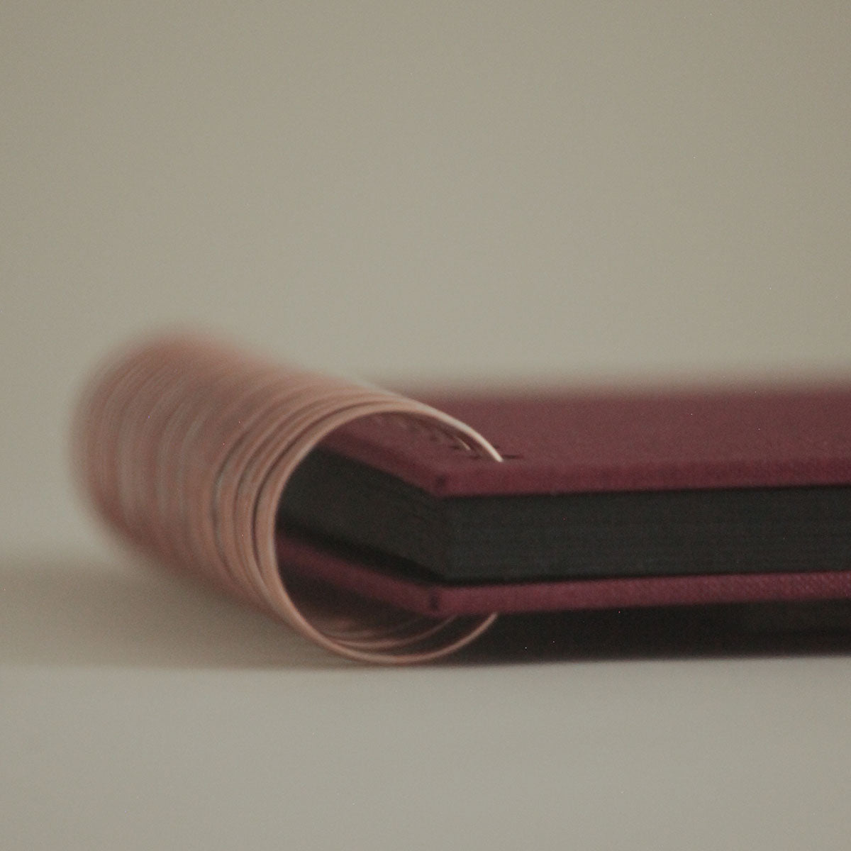 Spirala w kolorze miedzianym i fragment bordowego albumu na zdjęcia.