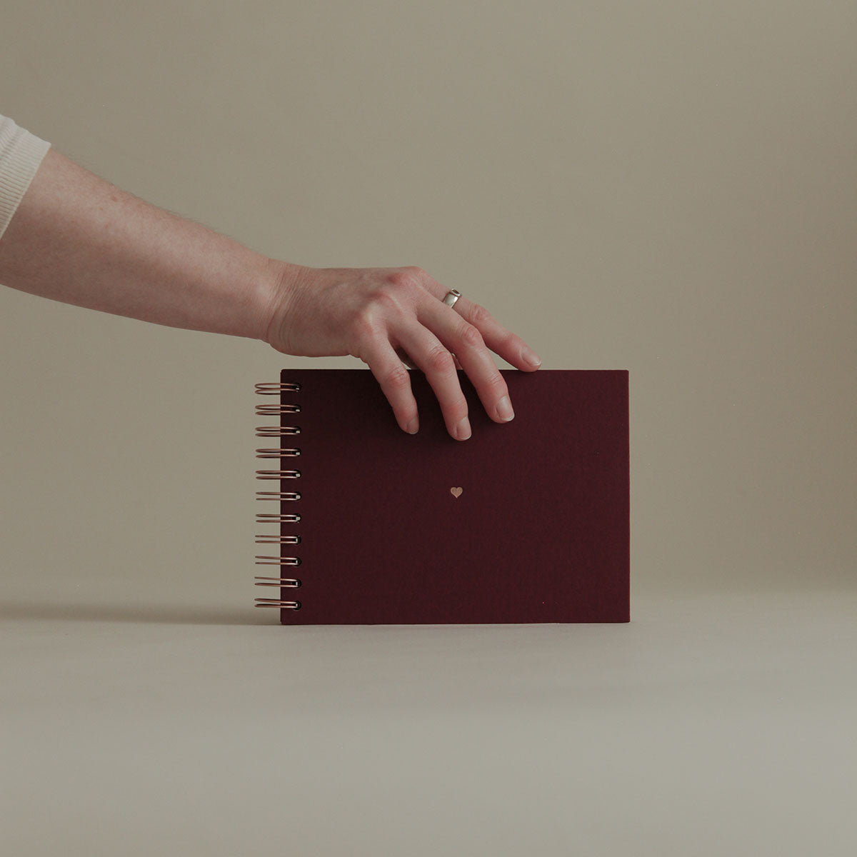 Bordowy album na zdjęcia od marki KAIKO. Album fotograficzny na spirali i ze złoconym serduszkiem na środku, w kolorze miedzianym.