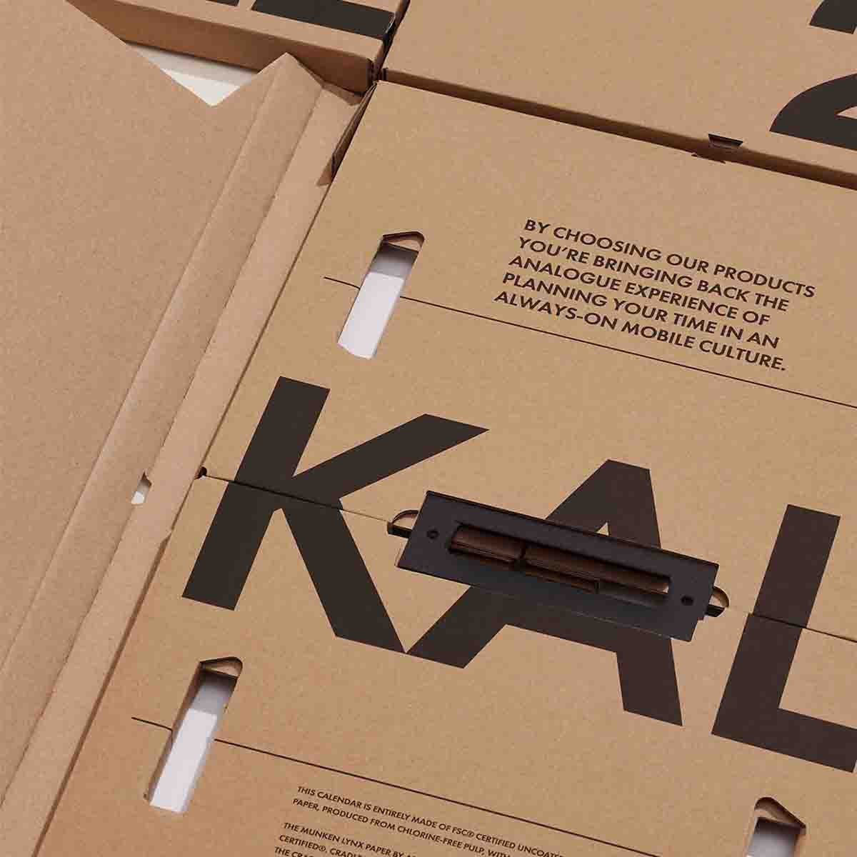 Bazowy karton z czarnymi napisami, w który pakowany jest kalendarz Kal.
