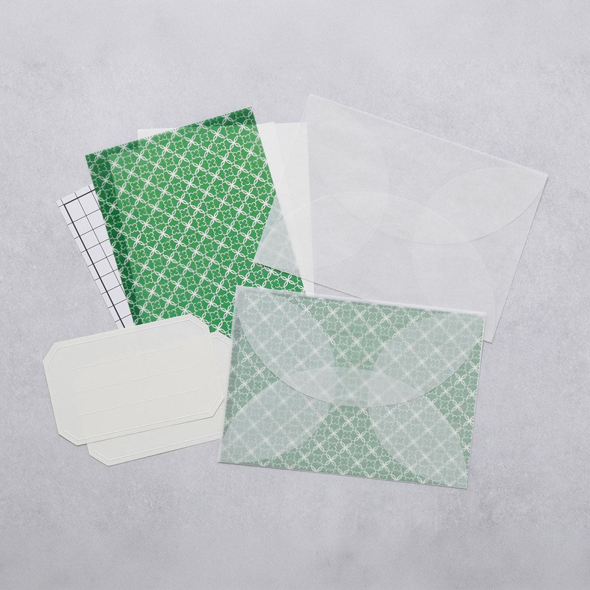 Zestaw do pisania listów z kopertami z półprzeźroczystego papieru i ozdobnymi arkuszami do zasłonięcia tekstu listu w kolorze zielonym oraz naklejkami do zaadresowania listu.
