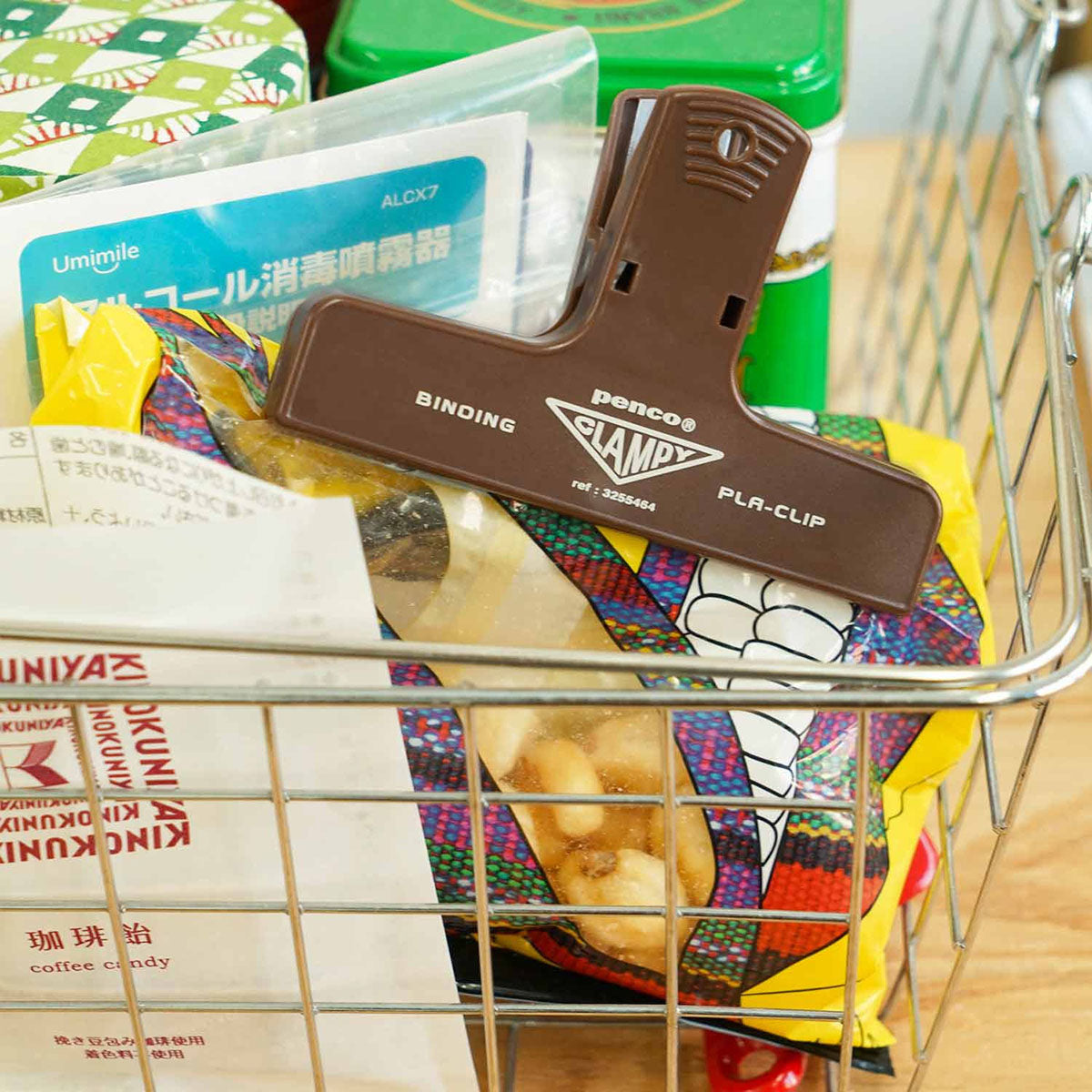 Plastikowy klips do papieru w kolorze brązowym z żółtym napisem, zamykający torebkę z przekąską.