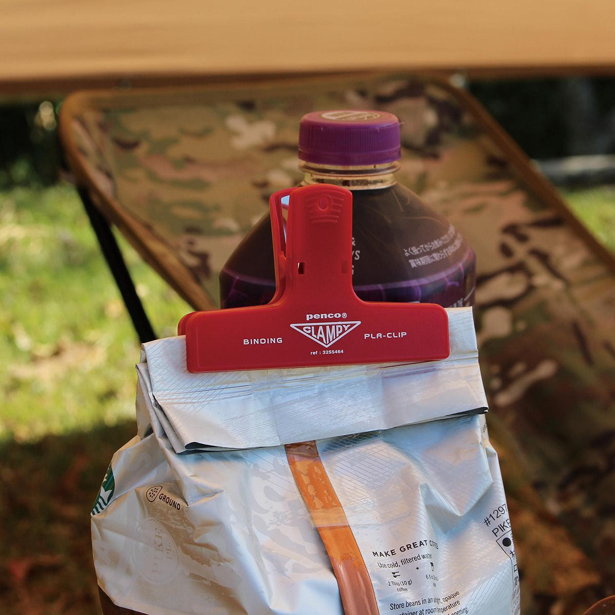 Plastikowy klips w kolorze czerwonym z czarnym napisem z nazwą marki Penco zamykający torebkę kawy.