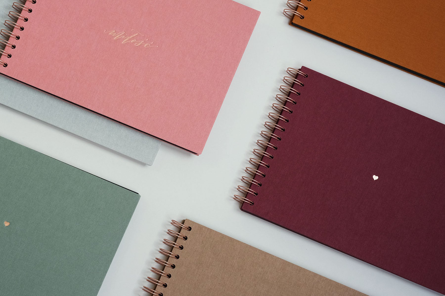 Kilka albumów na zdjęcia, w centralnej części płócienny album w kolorze bordowym na spirali w miedzianym kolorze.